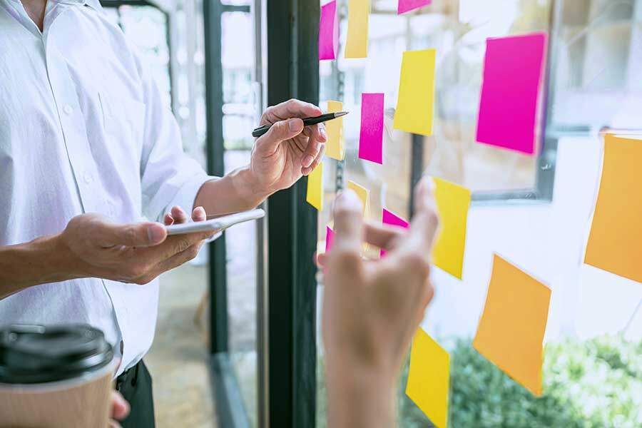 creative team using post it notes in glass wall to writing strategy